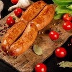Sausages on a wooden board with tomatoes and seasoning